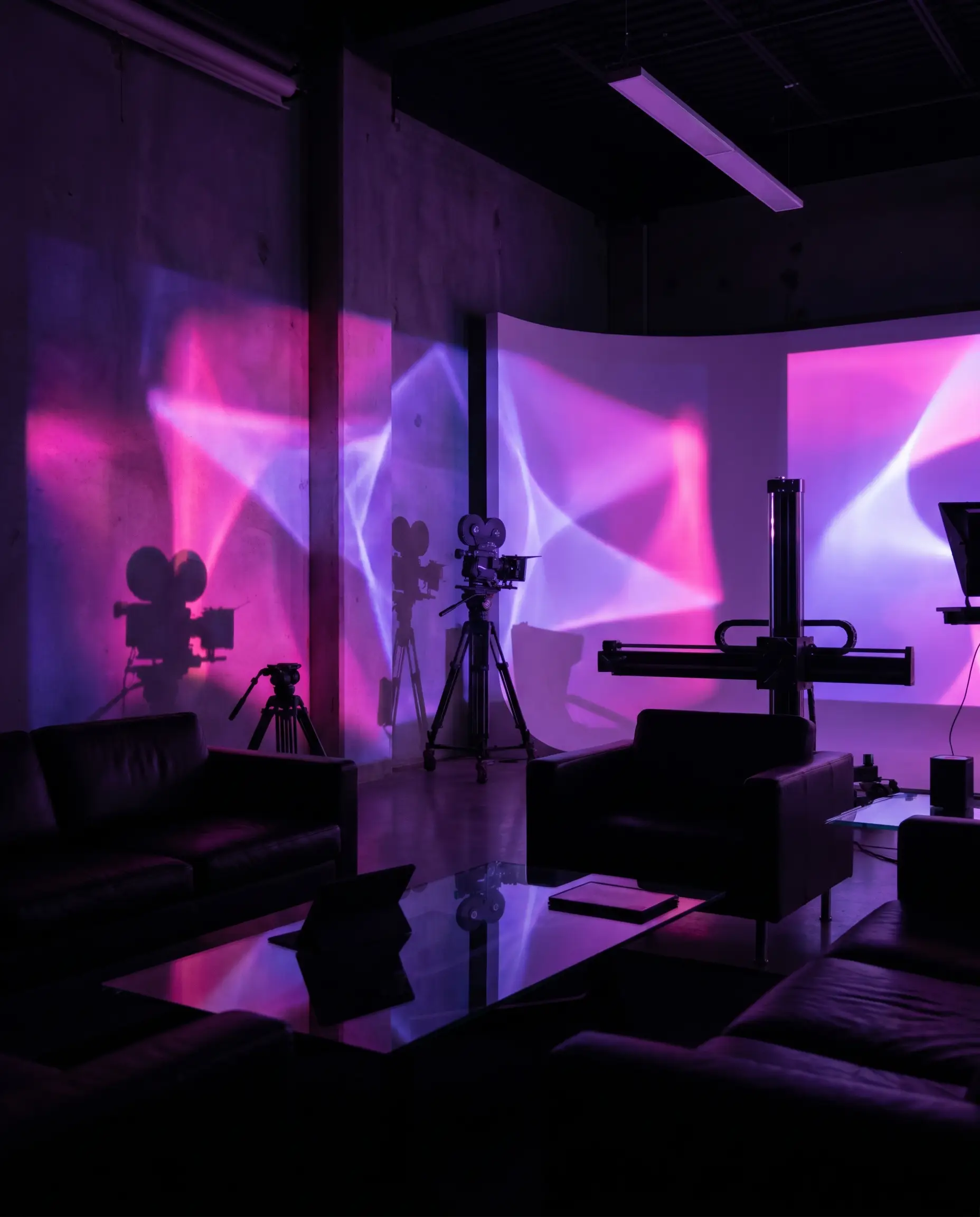 A dark editorial motion-design studio washed in magenta and violet light with abstract projected shapes.
